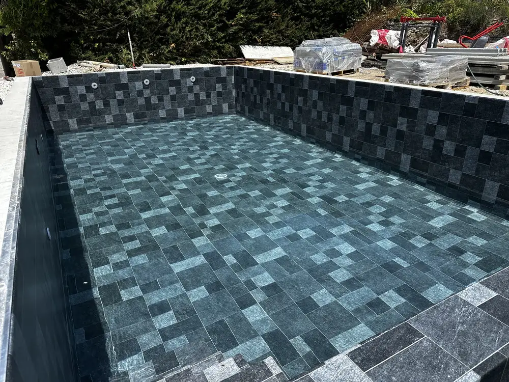Piscine en cours de remplissage avec membrane PVC armé imitation carrelage anthracite